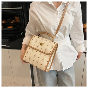Détail d'un sac bandoulière vintage crème avec motifs de lapins porté dans une cuisine chaleureuse