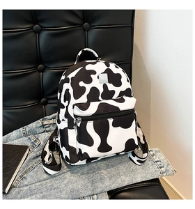 Detail of cow print backpack with adjustable straps and metal logo on denim texture
