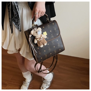 Détail du sac à dos vintage marron à motifs avec un joli pendentif ours en peluche