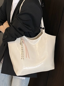 Minimalist beige glossy oil wax leather tote bag with brand lettering and woven pendants