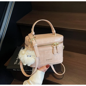 Detail of a pink box-style handbag with textures, dual zippers, and cute sheep charm