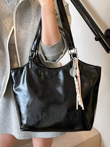 Minimalist black oil wax leather tote bag with sporty tennis racket pendant and shoulder strap
