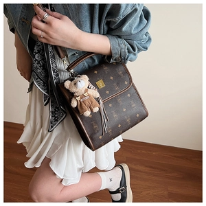 Détail d'un sac à main vintage marron avec logo bouclier doré et charmant ours
