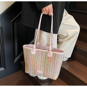 Detail view of colorful woven straw tote with pink leather straps for summer beach style