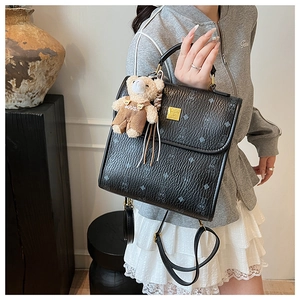 Détail du sac à dos en cuir noir avec motifs gaufrés et breloque ours mignonne