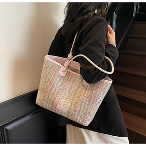 Detail of colorful hand-woven straw tote with pink leather handle and stylish knot design