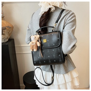 Détail d'un sac à dos noir en similicuir avec motif lapin et pendentif petit ours