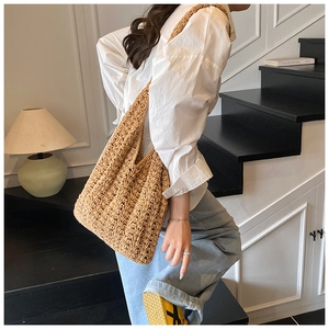 Detail shot of hand-woven hollow knit straw tote bag with clear texture and natural tan finish