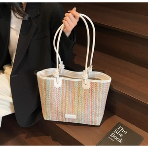 Detail of colorful striped straw tote with white leather straps and elegant side knots