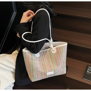 Close-up of colorful straw tote bag with white leather straps and knotted detail