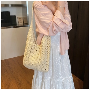 Detail of a beige crochet knit tote bag showing the hollow weave pattern on model