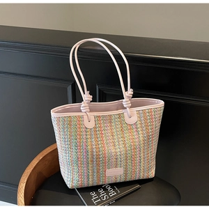 Close-up of rainbow striped straw tote bag featuring pink handles and knot detailing