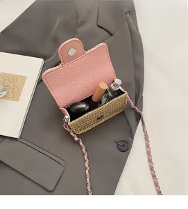 Mini straw square crossbody bag showing interior capacity with cosmetics on a gray suit