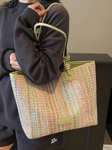 Colorful woven straw tote bag with green leather handles for beach and travel