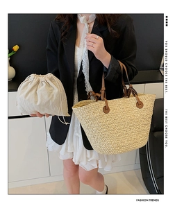 Straw woven tote bag with brown leather handles and inner drawstring pouch detail