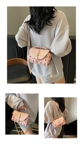 Close-up of pink monogram crossbody bag featuring a golden cylindrical rotating lock