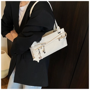 Gros plan d'un sac à bandoulière blanc avec boucles et un grand pendentif en étoile