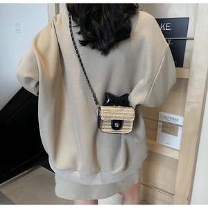 Detailed view of mini straw crossbody bag with black bow and floral metal clasp