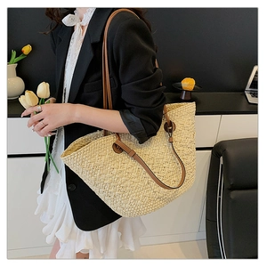 Close-up of woven straw tote bag with brown leather shoulder straps and large capacity