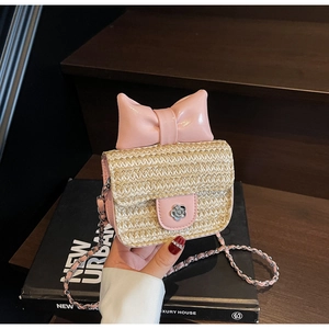 Detail of flower metal clasp and pink bow on straw crossbody bag with chain strap