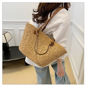 Detail of hand-woven straw tote bag with brown leather shoulder straps and natural texture