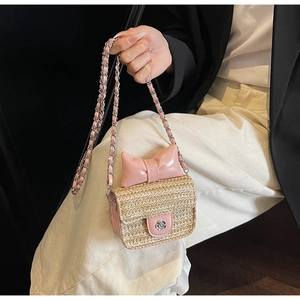 Detailed shot of mini straw bag featuring pink bow and silver camellia buckle