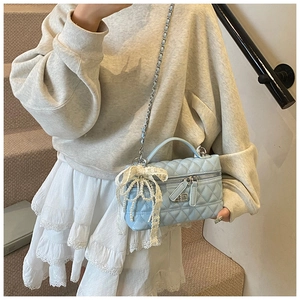 Detail of light blue quilted mini bag with silver chain and white lace pearl bow