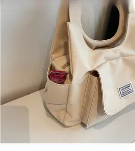 Detail view of canvas shoulder bag side pocket showing storage capacity and clean stitching