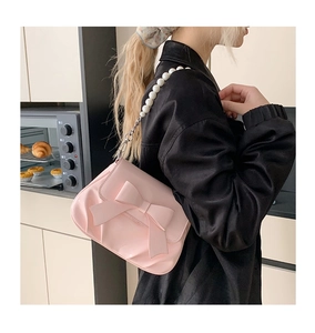 Detail view of pink bow shoulder bag with large pearls and elegant metal chain strap