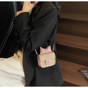 Detail of a mini straw crossbody bag with pink bow and silver camellia flower buckle
