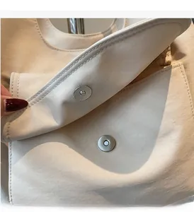 Close-up of magnetic snap closure and silver hardware on minimalist canvas shoulder bag