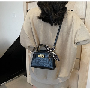 Détail du sac à main noir en cuir gaufré crocodile avec fermoir doré et foulard en soie