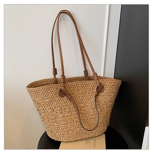 Detailed view of woven straw tote bag texture and high-quality brown faux leather straps