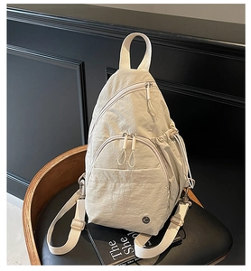 Détail du sac de poitrine en nylon crème avec texture froissée et poches zippées