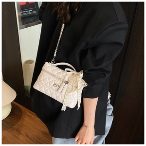 Detailed shot of white quilted chain bag featuring a large lace bow and silver turn lock