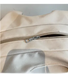 Detailed macro view of the smooth silver metal zipper on a beige canvas tote bag