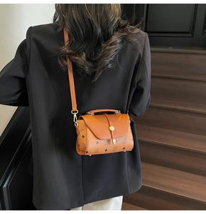 Close-up of vintage brown printed crossbody bag with golden metal buckle on a model