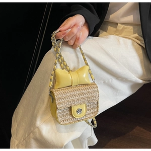 Close-up of straw mini bag featuring a yellow patent bow and silver flower buckle