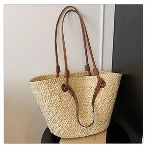 Close-up of the woven texture and brown leather strap detail on this straw tote bag