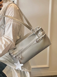Sac sous le bras argenté avec pendentif étoile sur mannequin devant mur blanc chic