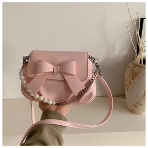 Detail of pink patent leather handbag with a large bow and elegant pearl chain strap