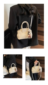 Dettaglio della borsa in ecopelle bianco crema con fibbie in metallo e ciondolo a bambolina