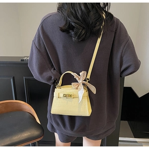 Détail du sac Kelly jaune clair avec texture crocodile, foulard en soie et fermoir doré