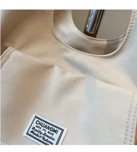 Detail of minimalist beige canvas shoulder bag showing soft fabric texture and stitching
