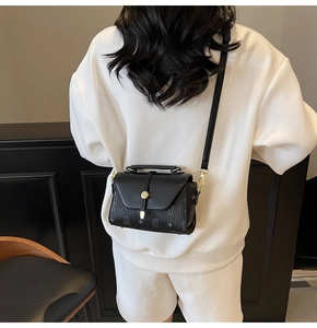 Detailed back view of a luxury black crossbody bag with monogram print and golden hardware