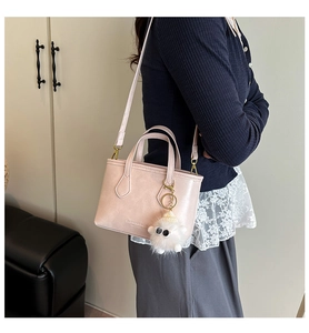 Detailed view of pink PU leather bucket bag with plush charm and detachable strap