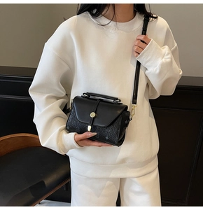 Classic black square handbag with golden spherical lock shown on a female model