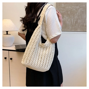 Close-up of beige hand-woven tote bag with elegant crochet hollow pattern design