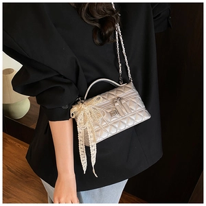 Detailed macro view of silver quilted leather bag with pearl lace bow charm