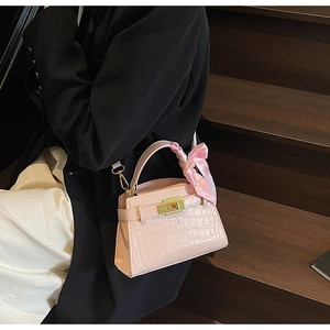 Détail du sac à main rose à motif crocodile avec fermoir doré et foulard en soie